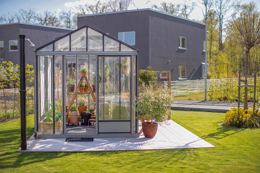 Euro Maxi Gewächshaus in Aluminium Natur auf einer Terrasse vor einem Wohnhaus