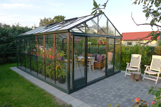 Euro Plus Gewächshaus in Tannengrün auf einer Terrasse, als Gartenzimmer eingerichtet