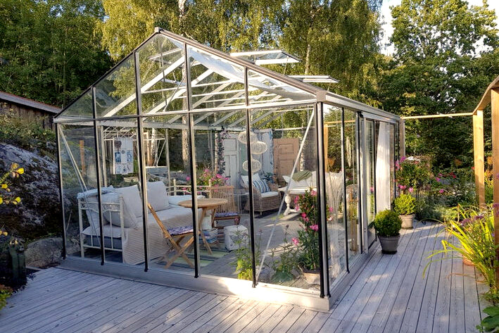 Euro Plus Gewächshaus in Aluminium Natur auf einer Holzterrasse, als Gartenzimmer eingerichtet